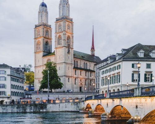 Photo of Zurich Grossmünster with its iconic twin towers along the Limmat River, one of the top sights on guided walking tours through Zurich's Old Town.