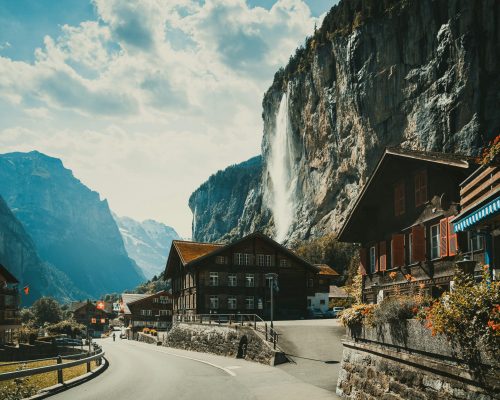 Beautiful view of Lauterbrunnen Valley with Staubbach Falls cascading down dramatic cliffs, traditional Swiss chalets, and alpine scenery — featured on Zurich Private Tours.