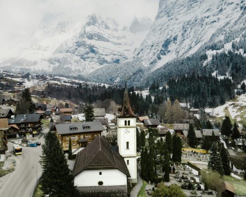 Beautiful winter view of Grindelwald village with church tower, traditional Swiss chalets, and snow-covered Bernese Alps in the background — featured on Zurich Private Tours.